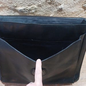 Puede incluir: Malet&iacute;n de cuero negro con interior abierto y m&uacute;ltiples bolsillos. La bolsa tiene forma rectangular con cierre de solapa y asa. El interior est&aacute; forrado con una tela oscura. El malet&iacute;n est&aacute; dise&ntilde;ado para transportar documentos y otros elementos esenciales.