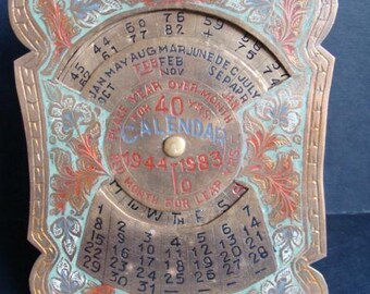 Pode incluir: Calendário vintage de latão de 40 anos, com um design floral decorativo com detalhes em vermelho, azul e verde. O calendário mostra meses, dias e um intervalo de anos de 1944 a 1983. Possui um mostrador giratório para selecionar o ano e o mês.