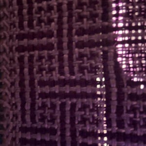 Puede incluir: Primer plano de una tela tejida con un patr&oacute;n geom&eacute;trico en tonos morados. La textura parece ser un tejido apretado, con un brillo sutil. El dise&ntilde;o presenta formas entrelazadas, creando una superficie texturizada.