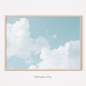 May include: A framed print of a light blue sky with white clouds. The frame is made of light wood.