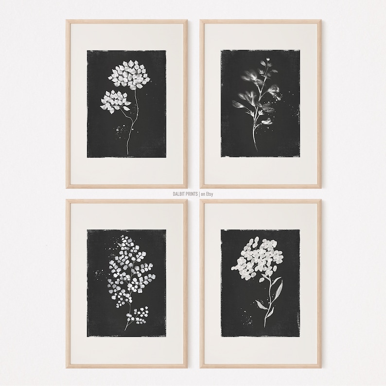 May include: Set of four black and white botanical prints featuring different floral and leafy designs. The prints are framed in a light wood frame and are arranged in a grid pattern.
