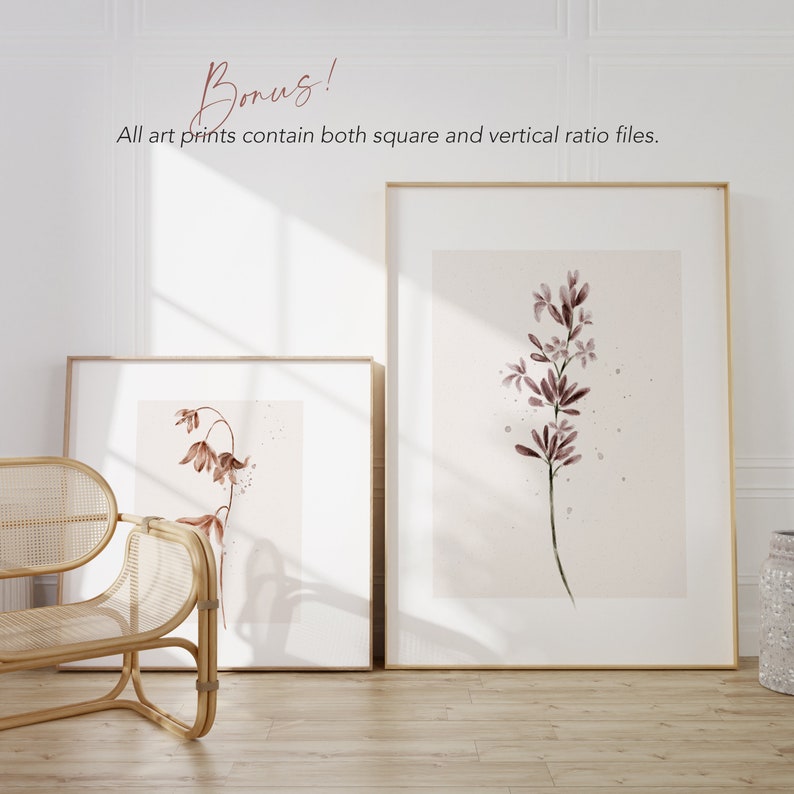 May include: Two framed watercolor prints of delicate pink flowers on a white background. The prints are in gold frames and are hanging on a white wall.