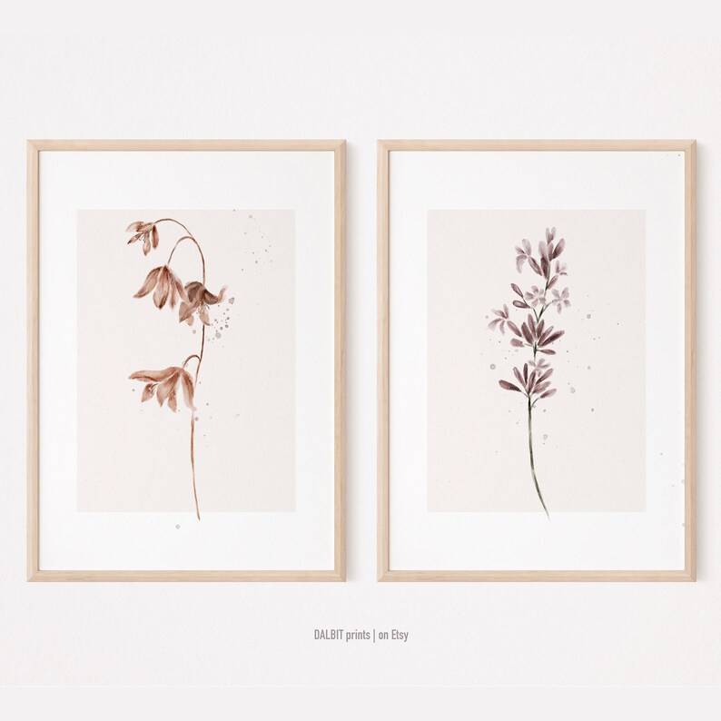 May include: Two framed watercolor prints of botanical illustrations. The print on the left features a brown flower with a delicate stem. The print on the right features a purple flower with a delicate stem.