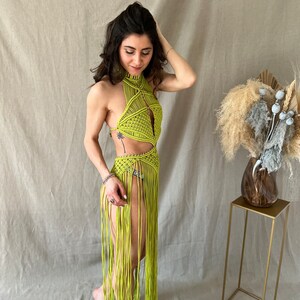 May include: A lime green crochet halter top with a long fringe skirt. The top has a geometric design and the skirt is made of long, thin strands of yarn.