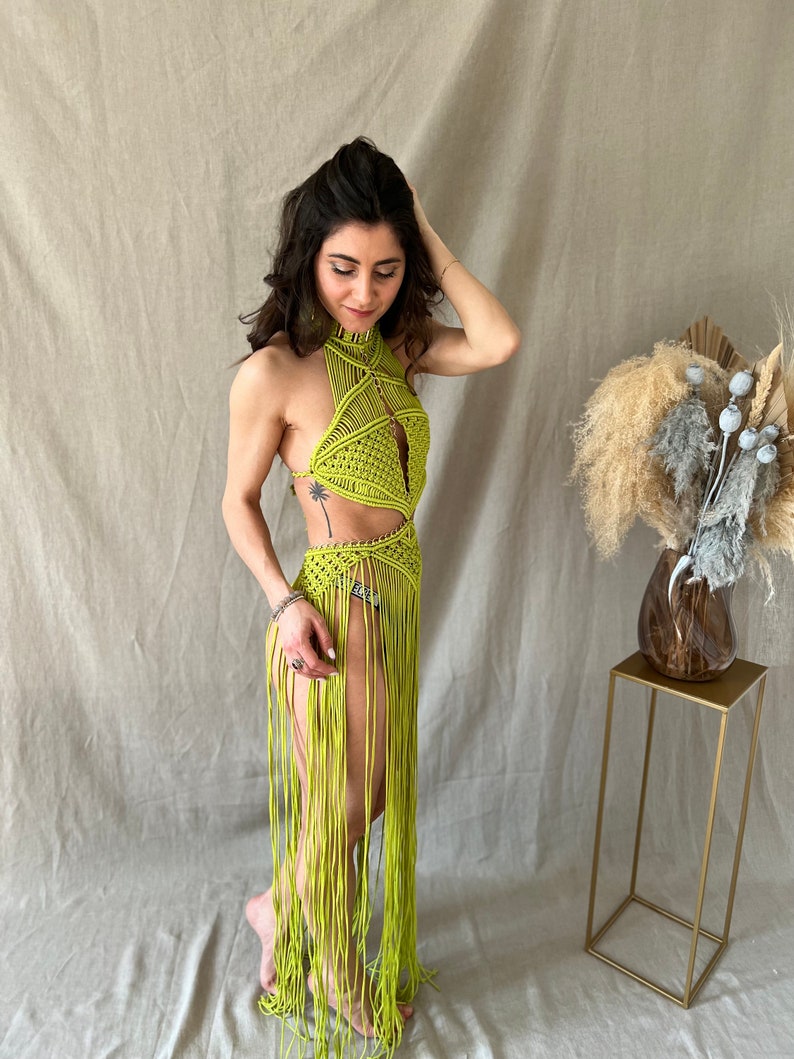 May include: A lime green crochet halter top with a long fringe skirt. The top has a geometric design and the skirt is made of long, thin strands of yarn.