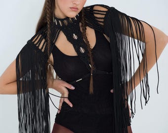 Peut inclure: Un haut crocheté noir avec des détails en franges. Le haut est porté sur un body noir et associé à des collants bordeaux.