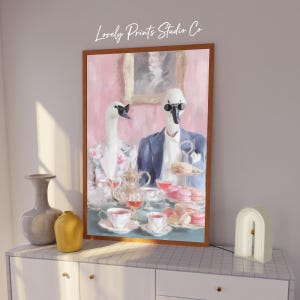 May include: Framed art print featuring two swans in formal attire, enjoying tea and macarons. The swans wear sunglasses and are set against a pink background. The print includes the text "Lovely Prints Studio Co."