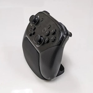 Peut inclure: Une manette de jeu sans fil noire avec une poignée texturée et plusieurs boutons. La manette comprend deux joysticks analogiques, une croix directionnelle et des boutons d'action. Le design est ergonomique pour un jeu confortable.