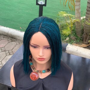May include: A teal blue wig with a straight bob style. The wig is on a mannequin head with a necklace.