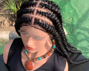 Pode incluir: Uma peruca preta trançada com uma frente de renda. A peruca é estilizada em um padrão de tranças quadradas com quatro tranças de cada lado. A peruca está em uma cabeça de manequim com um top preto sem mangas e um colar de contas.