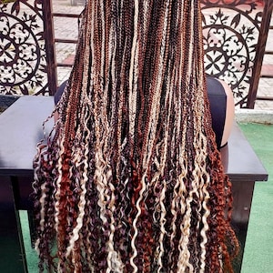 May include: Long, braided hairstyle with a mix of brown, blonde, and auburn strands. The braids transition into loose, curly ends, creating a layered effect. The hair is styled over a black top.