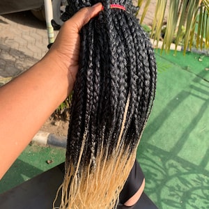 May include: Black and blonde ombre braiding hair. The hair is in long, thin braids with a black to blonde ombre effect.