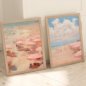 May include: Two framed paintings of beach scenes with pink umbrellas and people. The top painting shows a cloudy sky and the bottom painting shows a beach with pink umbrellas and people.