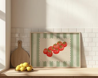 May include: A framed print depicting a bunch of red tomatoes. The artwork has a cream-coloured background with a scalloped edge and green striped border. The print is displayed on a wooden surface.