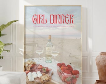 Könnte beinhalten: Ein gerahmter Druck mit dem Text "Girl Dinner" in rosa und roten Buchstaben. Der Text ist vor dem Hintergrund einer Strandszene mit einem Picknickkorb, einer Weinflasche und Erdbeeren platziert.