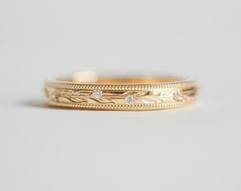 May include: A gold wedding band with a delicate engraved design and small diamonds set into the band.