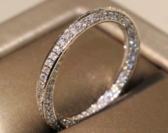 May include: A silver band ring with a row of small, clear diamonds encircling the band.