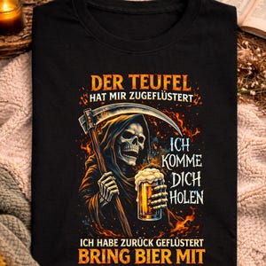 Puede incluir: Camiseta negra con un diseño de la Muerte con una guadaña y una jarra de cerveza. El texto en la camiseta dice: "DER TEUFEL HAT MIR ZUGEFLÜSTERT", "ICH KOMME DICH HOLEN" y "ICH HABE ZURÜCK GEFLÜSTERT BRING BIER MIT".
