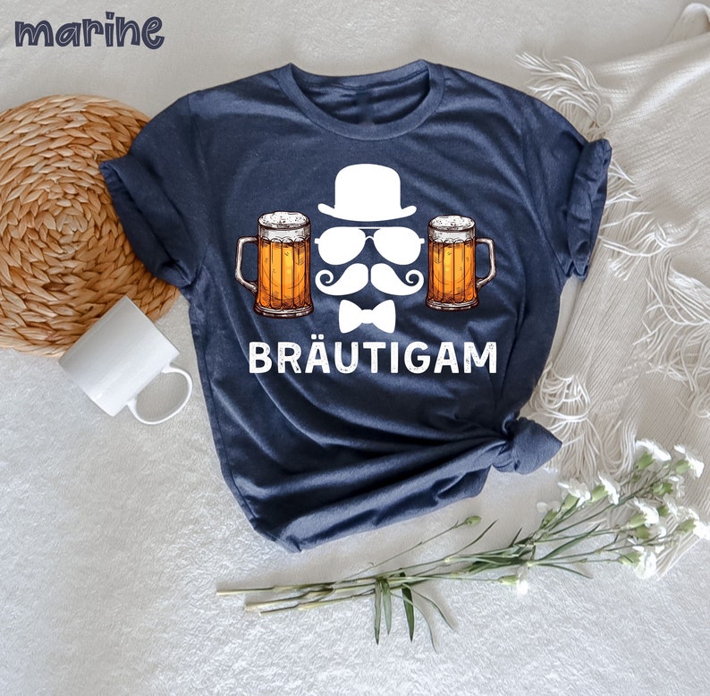 K&ouml;nnte beinhalten: Marineblaues T-Shirt mit einer Grafik von Hut, Sonnenbrille, Schnurrbart, Fliege und zwei Bierkr&uuml;gen. Das Wort "BR&Auml;UTIGAM" ist unter der Grafik aufgedruckt. Das Wort "marine" befindet sich in der oberen linken Ecke.