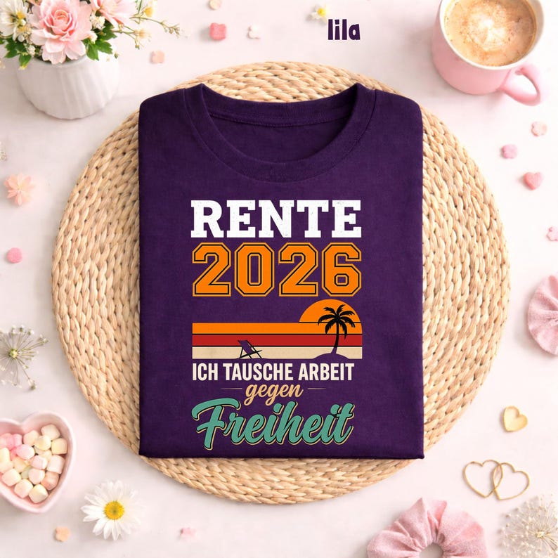 May include: A purple t-shirt with the text "RENTE 2026" in white and orange. Below the text is a sunset graphic with a palm tree. The text "ICH TAUSCHE ARBEIT gegen Freiheit" is below the sunset graphic.