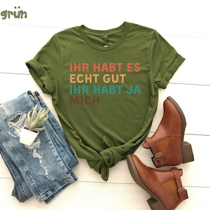 May include: A green t-shirt with the text "Ihr habt es echt gut ihr habt ja mich" in rainbow colors.