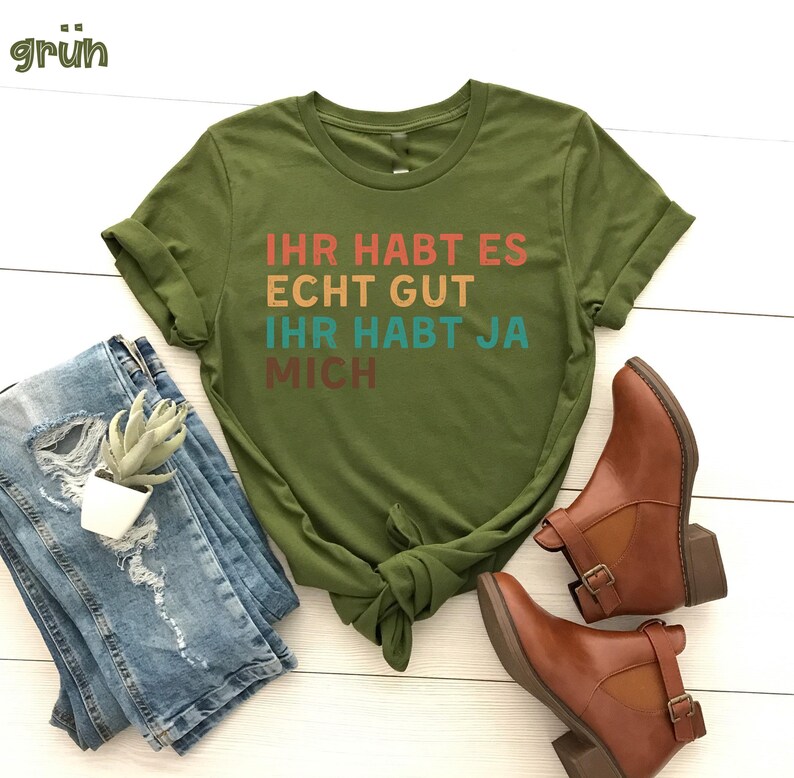 May include: A green t-shirt with the text "Ihr habt es echt gut ihr habt ja mich" in rainbow colors.