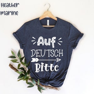 May include: A dark blue t-shirt with white text that reads "Auf Deutsch Bitte" with an arrow pointing to the right.