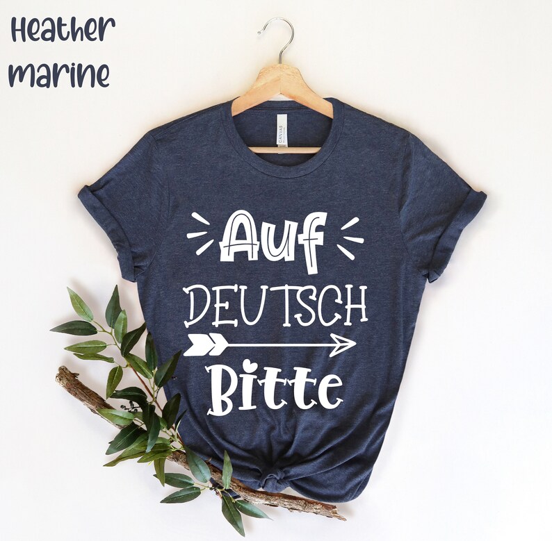 May include: A dark blue t-shirt with white text that reads "Auf Deutsch Bitte" with an arrow pointing to the right.