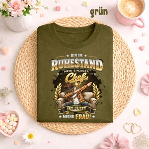 May include: Olive green t-shirt with the text "BIN IM RUHESTAND MEIN EINZIGER Chef IST JETZT MEINE FRAU!" in gold and white. The graphic features a cartoon man dabbing while seated in a chair. The word "gr&uuml;n" is in the top right corner.