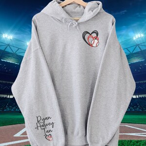 May include: Gray hooded sweatshirt with the names "Ryan Harvey Ian" and a baseball with two hearts on the sleeve.