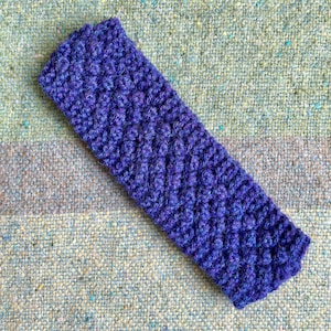 May include: A purple knitted headband with a textured pattern.