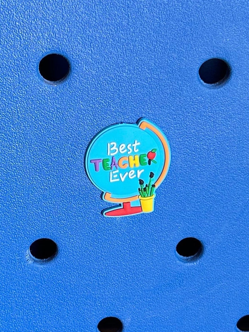 May include: A blue globe with the text "Best Teacher Ever" in rainbow colours. The globe has a red base and a green pot with yellow flowers.