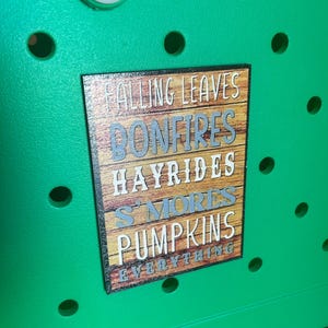 May include: Green storage bin with a wooden sign that says "Falling Leaves, Bonfires, Hayrides, S'mores, Pumpkins, Everything".