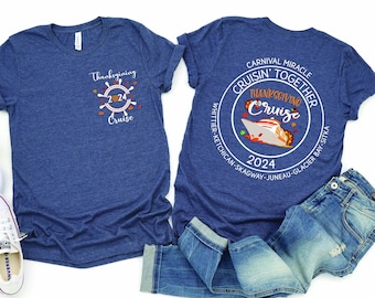May include: A blue t-shirt with a Thanksgiving cruise design. The front of the shirt says "Thanksgiving Cruise 2024" with a steering wheel and fall leaves. The back of the shirt says "Carnival Miracle Cruisin' Together Thanksgiving Cruise 2024" with a cruise ship and fall leaves. The shirt is on a white background with a pair of white sneakers and blue jeans.