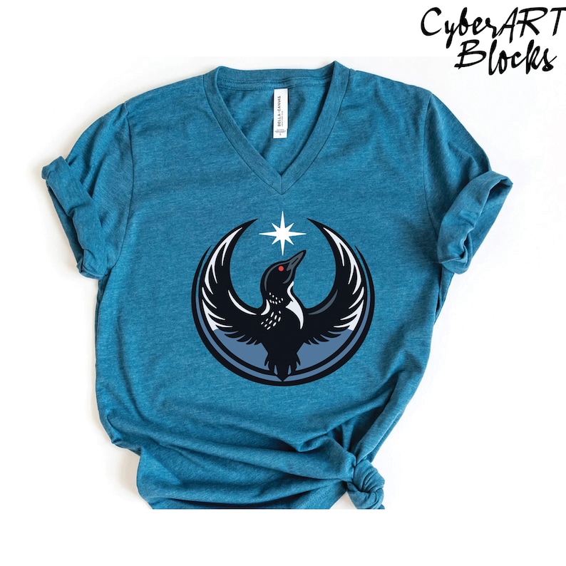 A blue t-shirt with a graphic design featuring a black bird with wings spread, a star, and a circular shape.