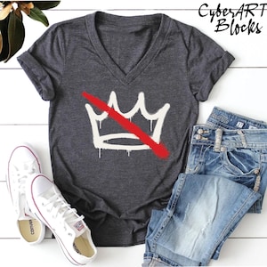 a gray v-neck t-shirt with a white crown graphic and a red diagonal line across it, along with a pair of blue jeans and white sneakers.