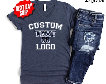 May include: A dark blue heathered V-neck t-shirt with the white text CUSTOM TEXT OR LOGO printed on the front. Next to the shirt are dark blue distressed denim jeans with a large rip on the thigh. A red starburst graphic says NEXT DAY SHIP.