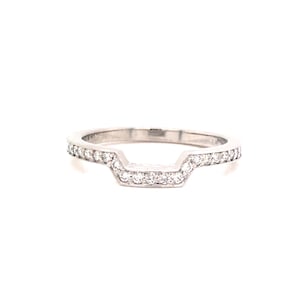 May include: A delicate, silver-toned wedding band with a unique, open-V design. The band is adorned with a row of sparkling, clear gemstones.