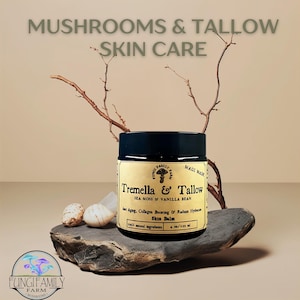 May include: A black jar with a white label that reads "Tremella & Tallow Sea Moss & Vanilla Bean Skin Balm" with the text "Anti-Aging, Collagen Boosting & Radiant Hydration 100% Natural Ingredients 4 oz/118 ml" below. The jar is sitting on a gray rock with a small branch behind it.