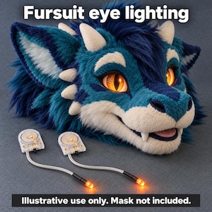 May include: A fursuit eye lighting kit featuring two small battery-operated modules with attached wires and glowing orange LED bulbs, shown with a blue and white dragon-like fursuit head mask. Text reads: Fursuit eye lighting. Illustrative use only. Mask not included.