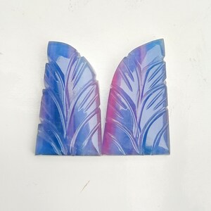 Könnte beinhalten: Ein Paar geschnitzte blaue und rosafarbene Edelsteinkabochons mit einem Blattdesign.