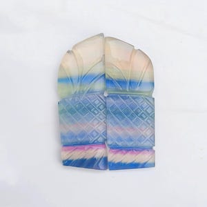 May include: Two carved gemstone cabochons featuring a rainbow of colours, including blue, green, pink, and white. The cabochons are carved with a geometric pattern and have a smooth, polished finish.