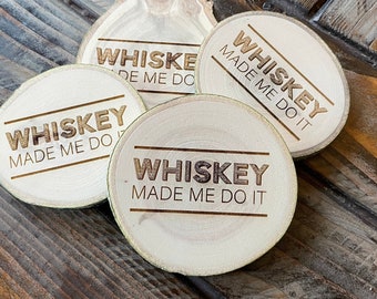 May include: Four round wooden coasters with the text "Whiskey Made Me Do It" burned into the surface. The coasters are arranged on a wooden surface.