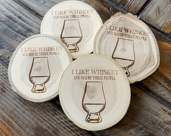 May include: Four wooden coasters with a laser-engraved design. Each coaster features a whiskey glass and the text "I like whiskey and maybe three people".