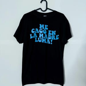 Puede incluir: Camiseta negra con un estampado gráfico azul que dice "ME CAGO EN LA MADRE LUMA!"
