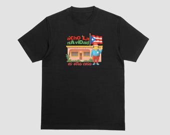 May include: Black t-shirt featuring a colorful graphic with the text "aCho La nAvidad es otra cosa". The graphic includes a cartoon character holding a Puerto Rican flag in front of a building.