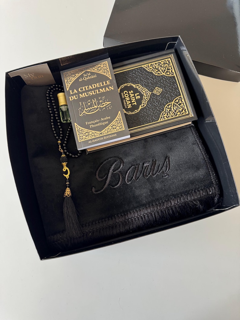 K&ouml;nnte beinhalten: Eine schwarze Geschenkbox mit einem schwarzen Gebetsteppich, auf dem der Name Baris schwarz eingestickt ist, einer schwarz-goldenen Gebetskette, einem kleinen Glasflakon f&uuml;r Parf&uuml;m sowie den B&uuml;chern La Citadelle du Musulman und Le Saint Coran.