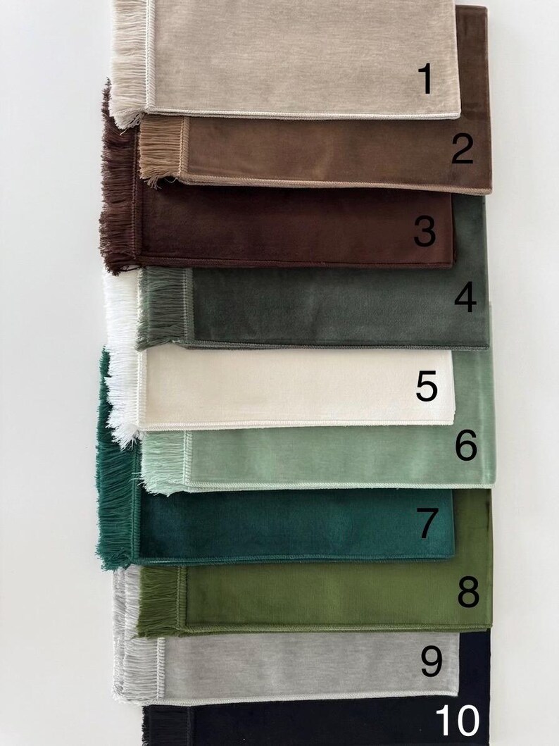 K&ouml;nnte beinhalten: Eine Sammlung von zehn rechteckigen Stoffmustern mit Fransen an der linken Seite, vertikal angeordnet. Jedes Muster hat eine einzigartige einfarbige Farbe, darunter Beige, Braun, Dunkelbraun, Grau, Wei&szlig;, Hellgr&uuml;n, T&uuml;rkis, Oliv, Silber und Schwarz.