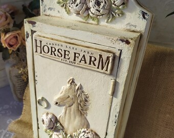 Può includere: Un portachiavi in legno bianco con una testa di cavallo e un design floreale. Il portachiavi ha un cartello che recita "Canyon Lake Farm Est. 1920".