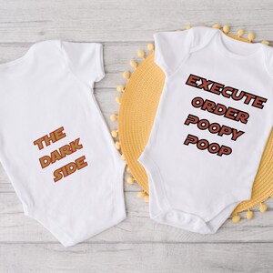 May include: Two white baby onesies with red text. One onesie says "The Dark Side" and the other says "Execute Order Poopy Poop".